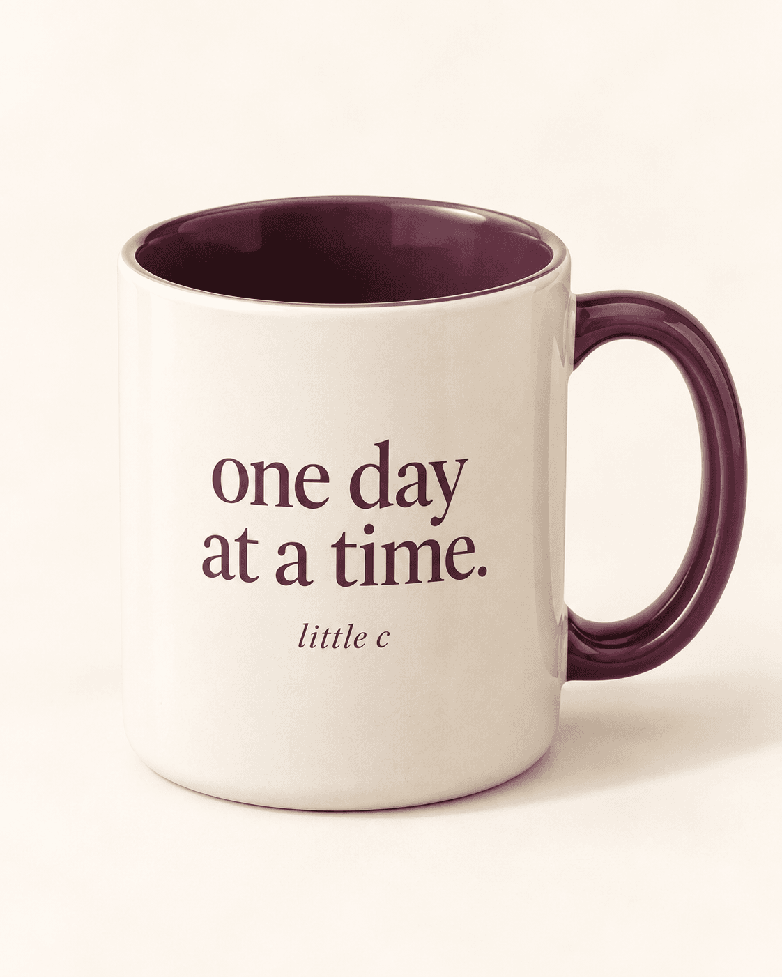 One day at a time mug — cream product mockup with “one day at a time.” lettering.